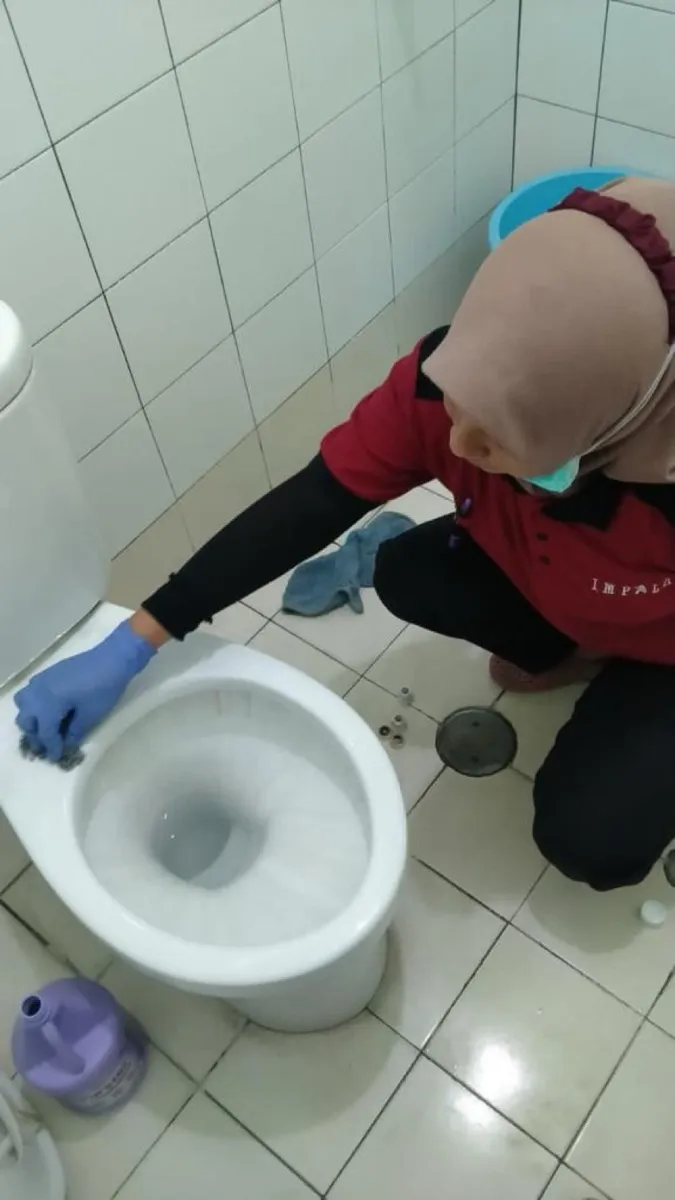 Petugas membersihkan toilet gedung