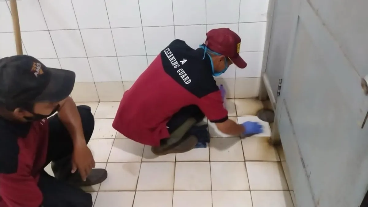 Petugas membersihkan lantai kamar mandi