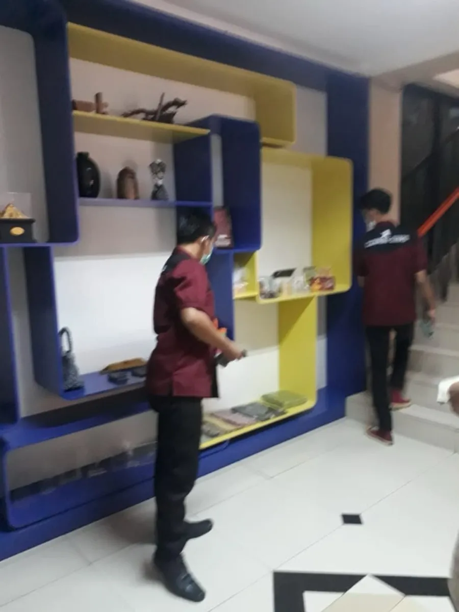 Petugas membersihkan rak pajangan di lobi kantor