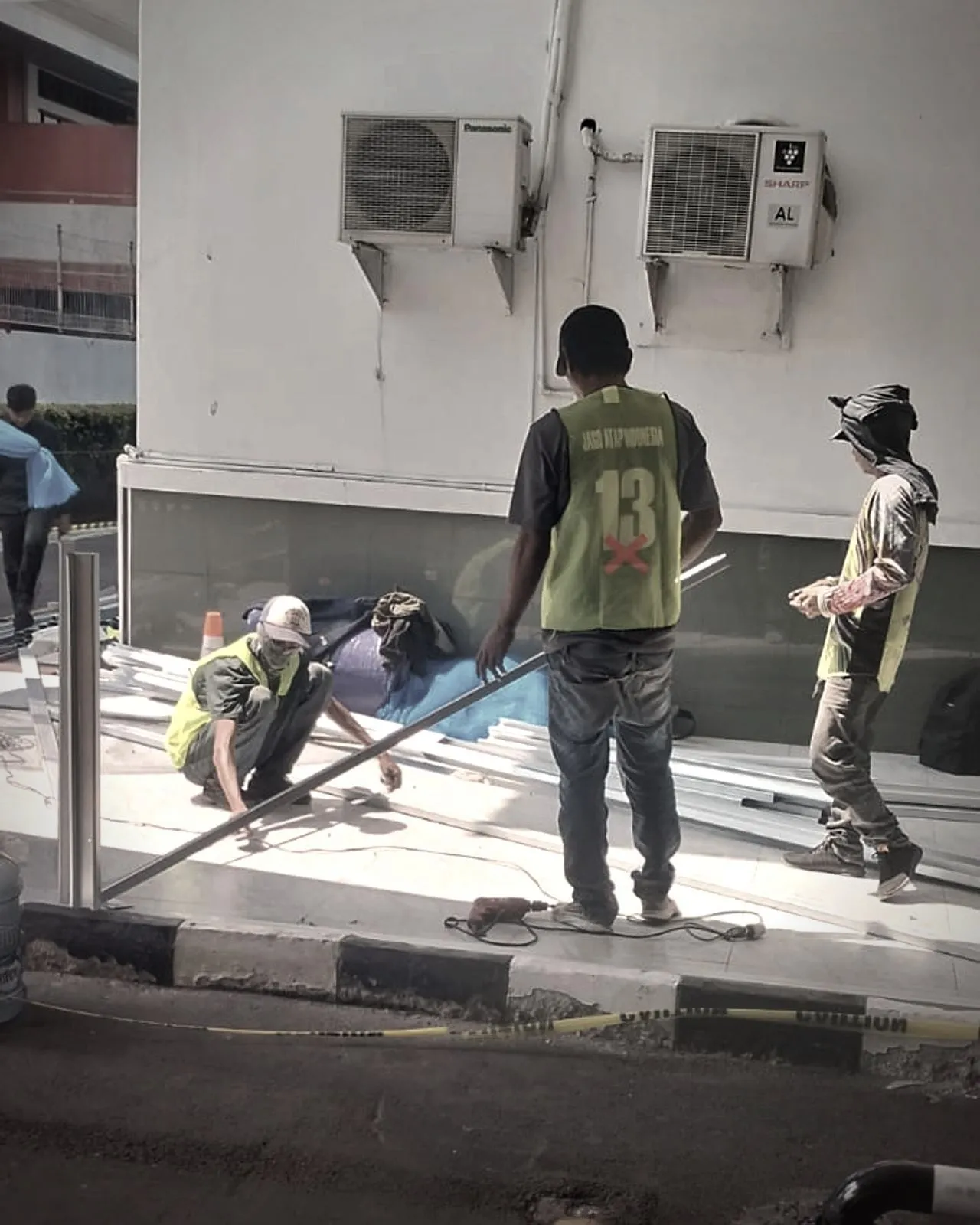 Pekerja berompi keselamatan memasang rangka di area gedung